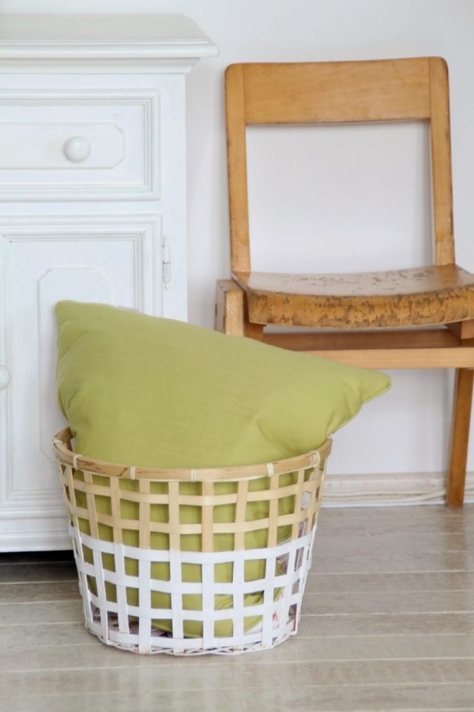 Stilleben mit altem Kinderstuhl und Ikea Gaddis Korb mit grünem Kissen