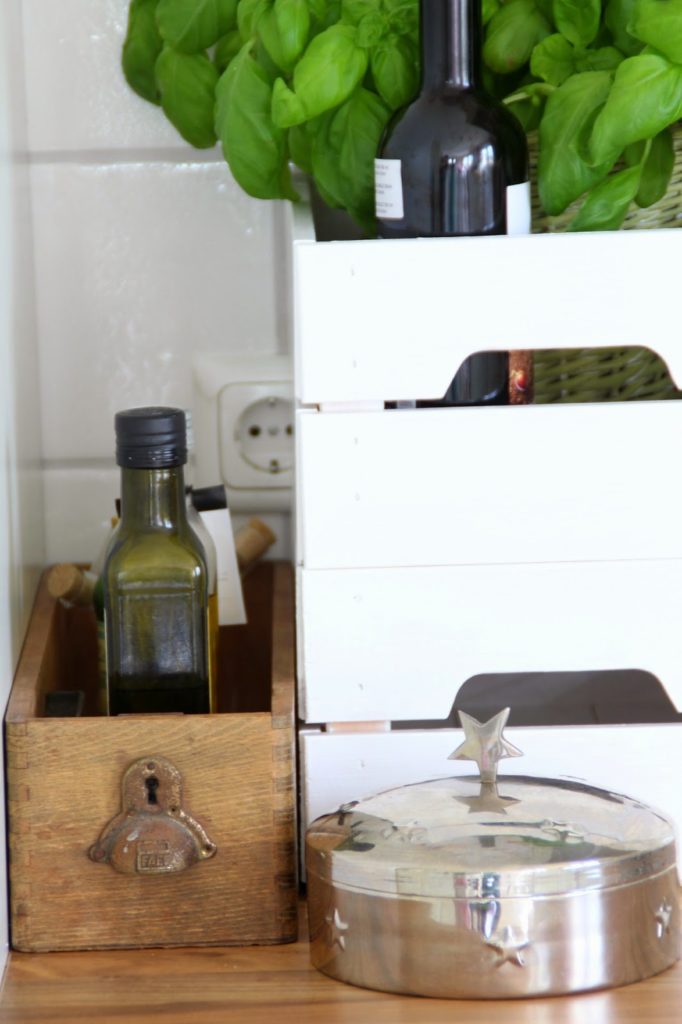 Links kleine braune Schublade als Küchenutensio für kleine Ölflaschen rechts Kiste Knagglig als Basilikumübertopf