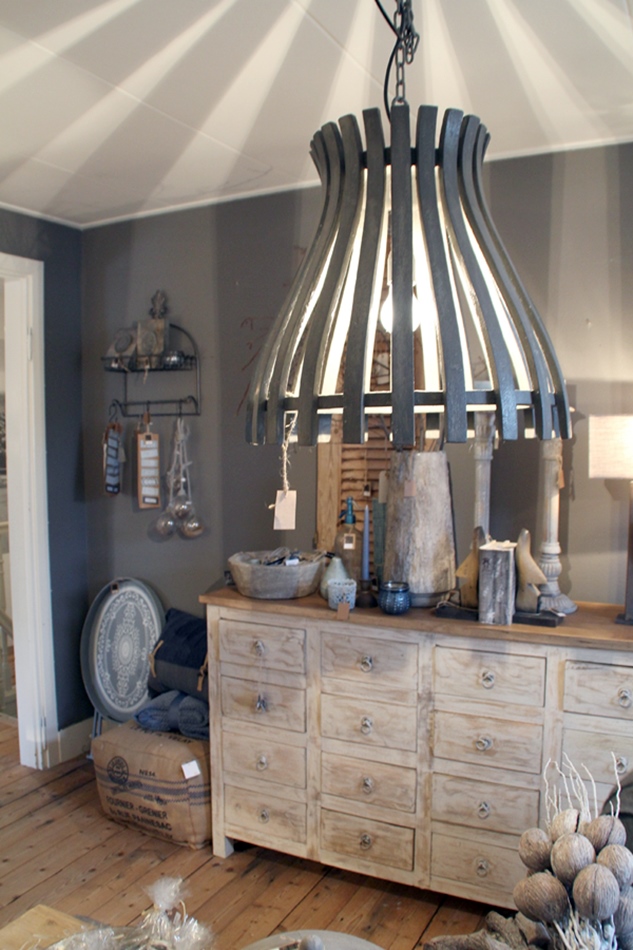 Riesige graue Lampe aus Holzplanken mit Kommode und Wohnaccessoires im Hintergrund in geige-grau