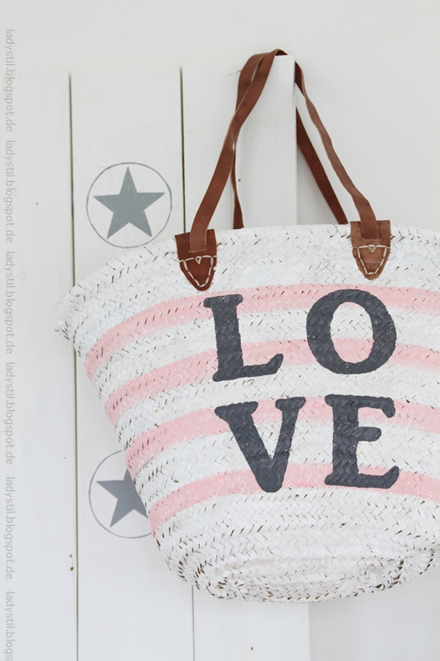 weiße rosa gestreifte Korbtasche mit großem anthrazitfarbenem Love Schriftzug an einer weißen Tafel mit grauen Sternen für den Bloggeroptimierungsfotowettbewerbbeipixum