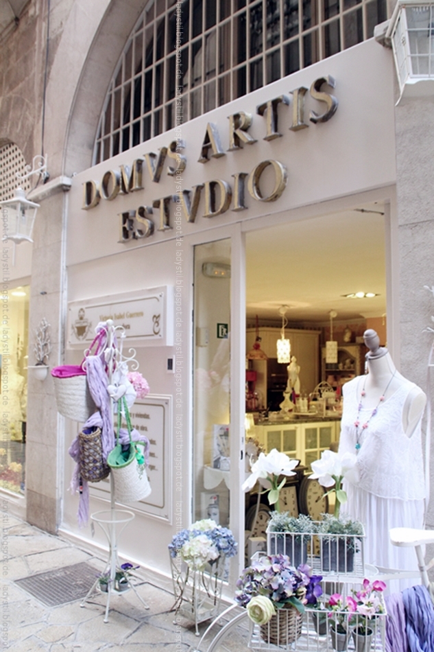 Blickk auf den Eingang des Interior Geschäfts Artis Domvs in Palma mit Ständer voller Korbtaschen 
