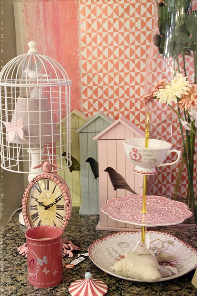 Wohnaccessoires in rosa und weiß im Interior Geschäft Domvs Artis in Palma Etagere Uhr Becher und Lampe vor gemusterter Tapete