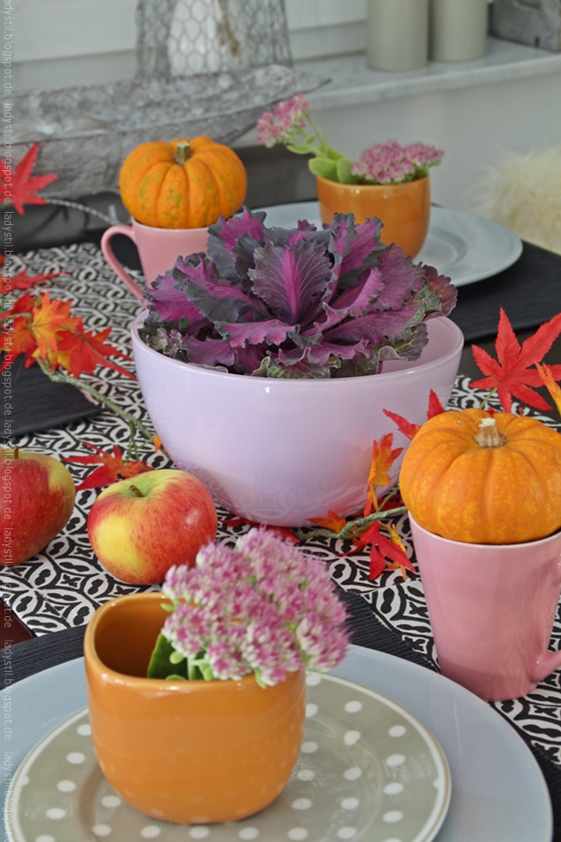 Herbstliche Tischdekoration in orange und purpur mit Kürbissen in orange