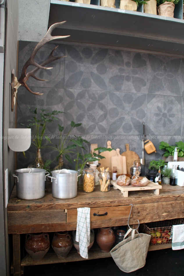 Holzküche mit grauen gemusterten Fliesen und weißen Küchenaccessoires auf der vt wonen en design beurs in Amsterdam 2015