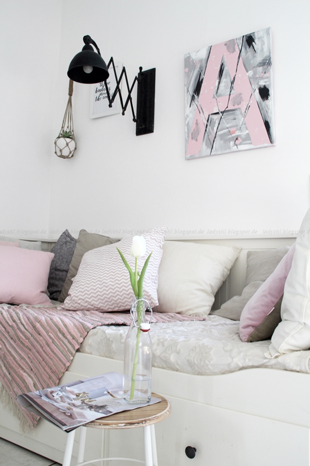 Daybed mit weißen beigen rosafarbenen Kissen, einem Hocker mit Tulpe in einer Flasche und darüber hängt eine schwarze Scherenlampe sowie ein DIY Typo Letters Acrylbild
