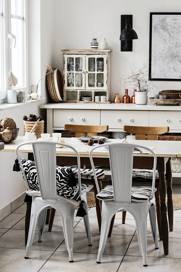 Kücheneinrichtung in Schwarz Weiß Holz mit leichten New Boho Elementen, weißer Küchentisch mit weißen Stühlen Voga