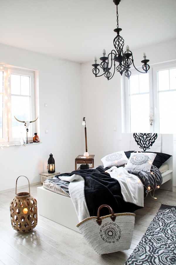 Schlafzimmerdeko im New Boho Look mit schwarz-weißen Ethnoelementen und Holz Accessoires, Bohoschädel, afrikanische Maske und Bambus-Laterne