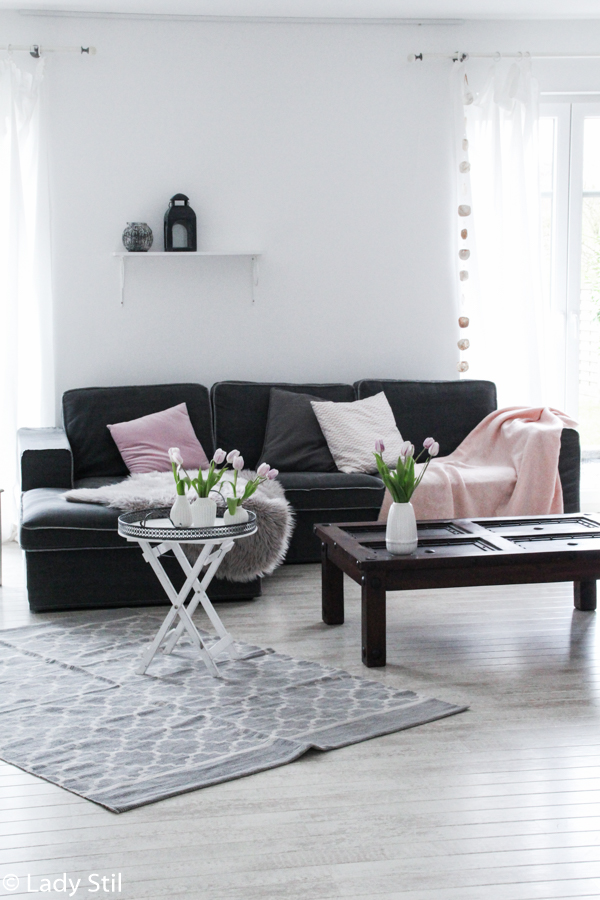 wie man mit wenigen Mitteln ein monocromes Zuhause in ein frühlingshaftes, fröhliches Interior-Ambiente verwandelt, Wohnzimmer Sofa mit rosa Kissen und Plaid